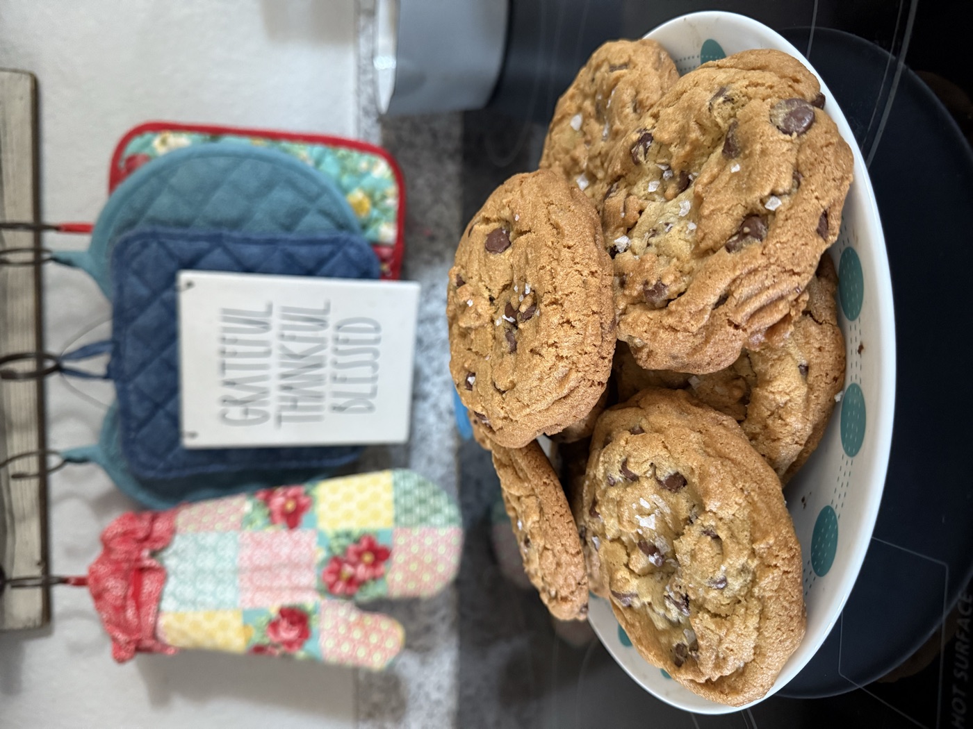 Plate piled with thick chocolate chip cookies on a kitchen counter