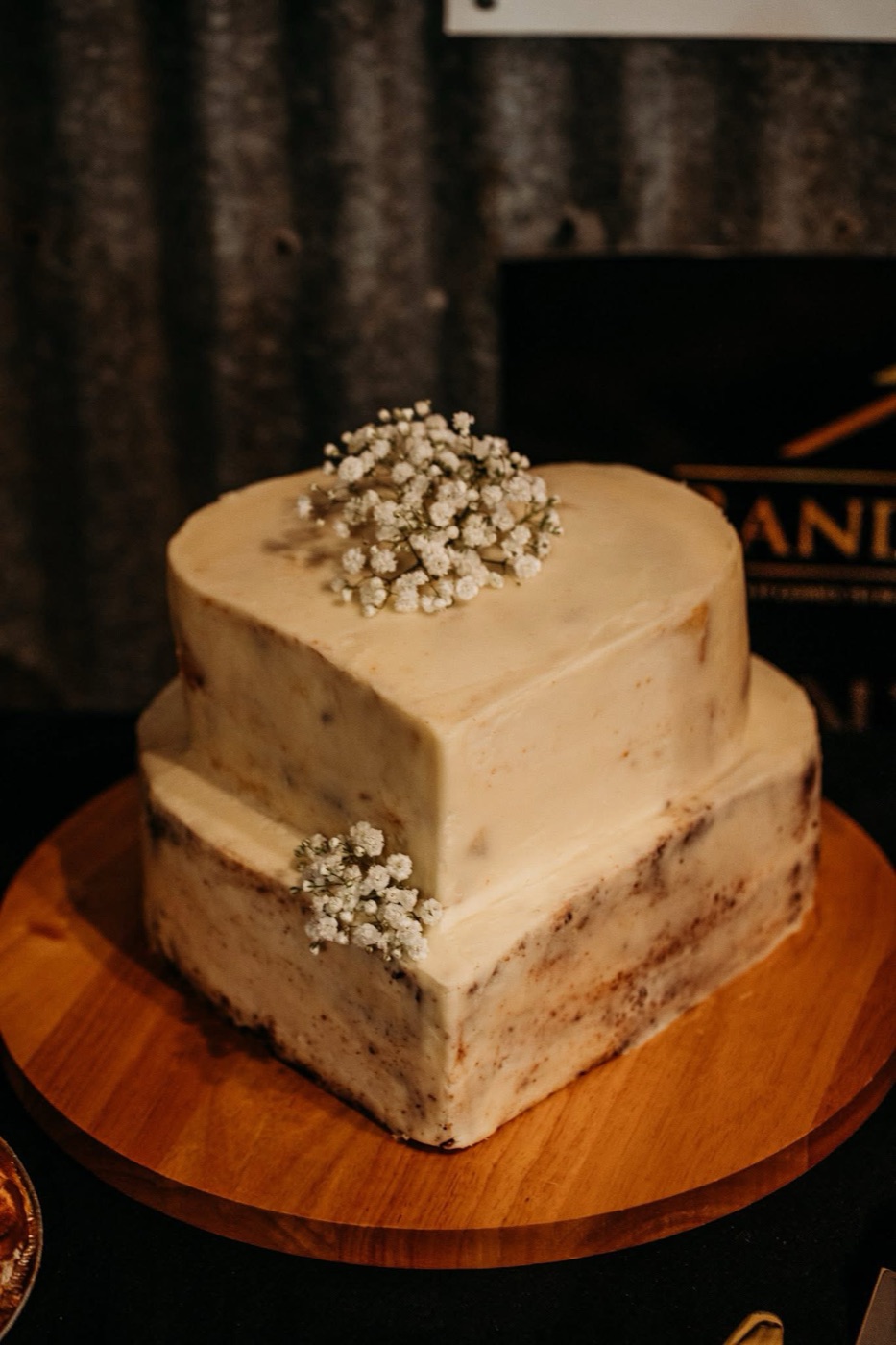 Two-tier naked vanilla wedding cake trimmed with sprigs of baby&rsquo;s breath